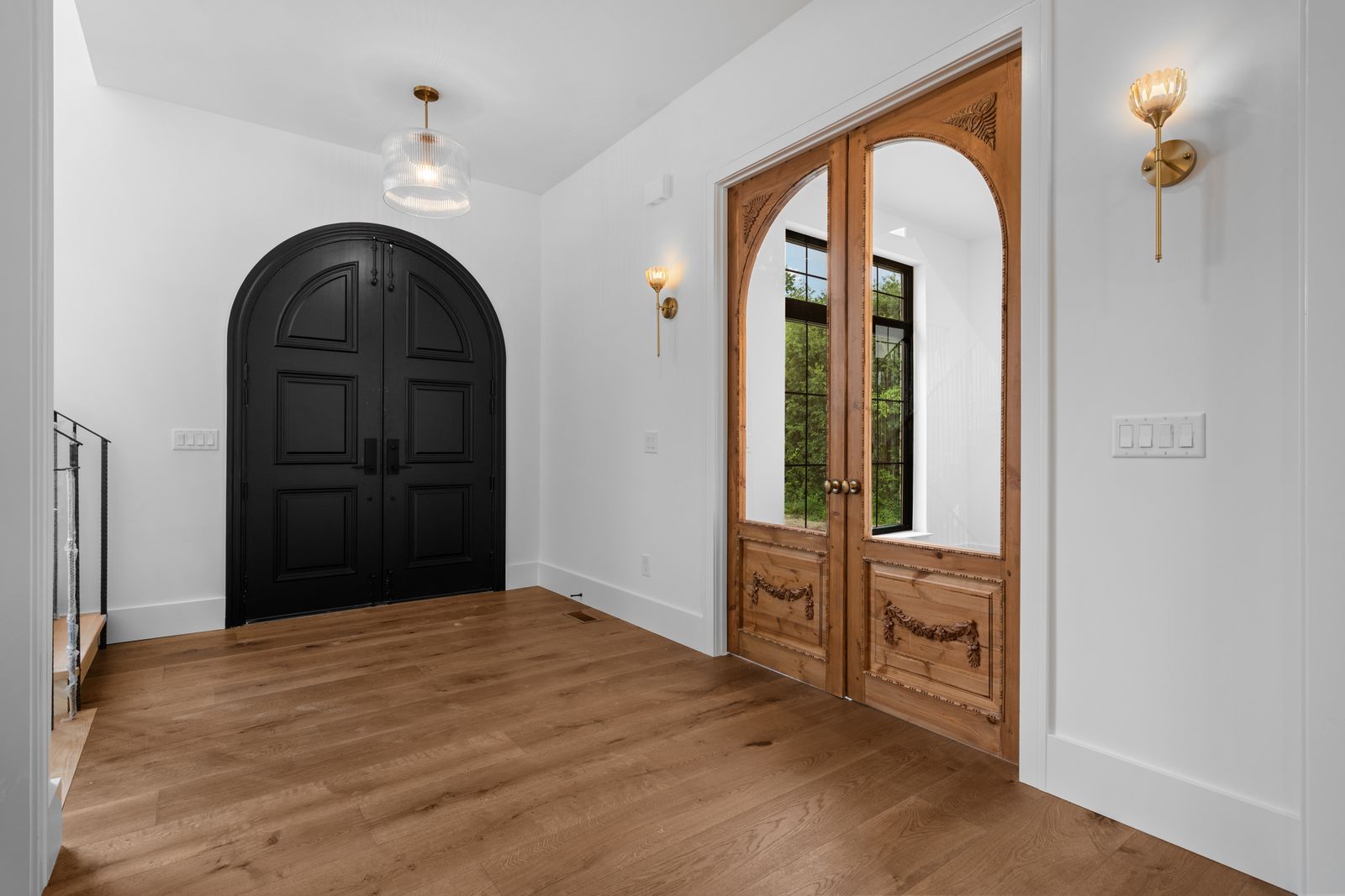 Foyer detail with arched doors and iron stair railing